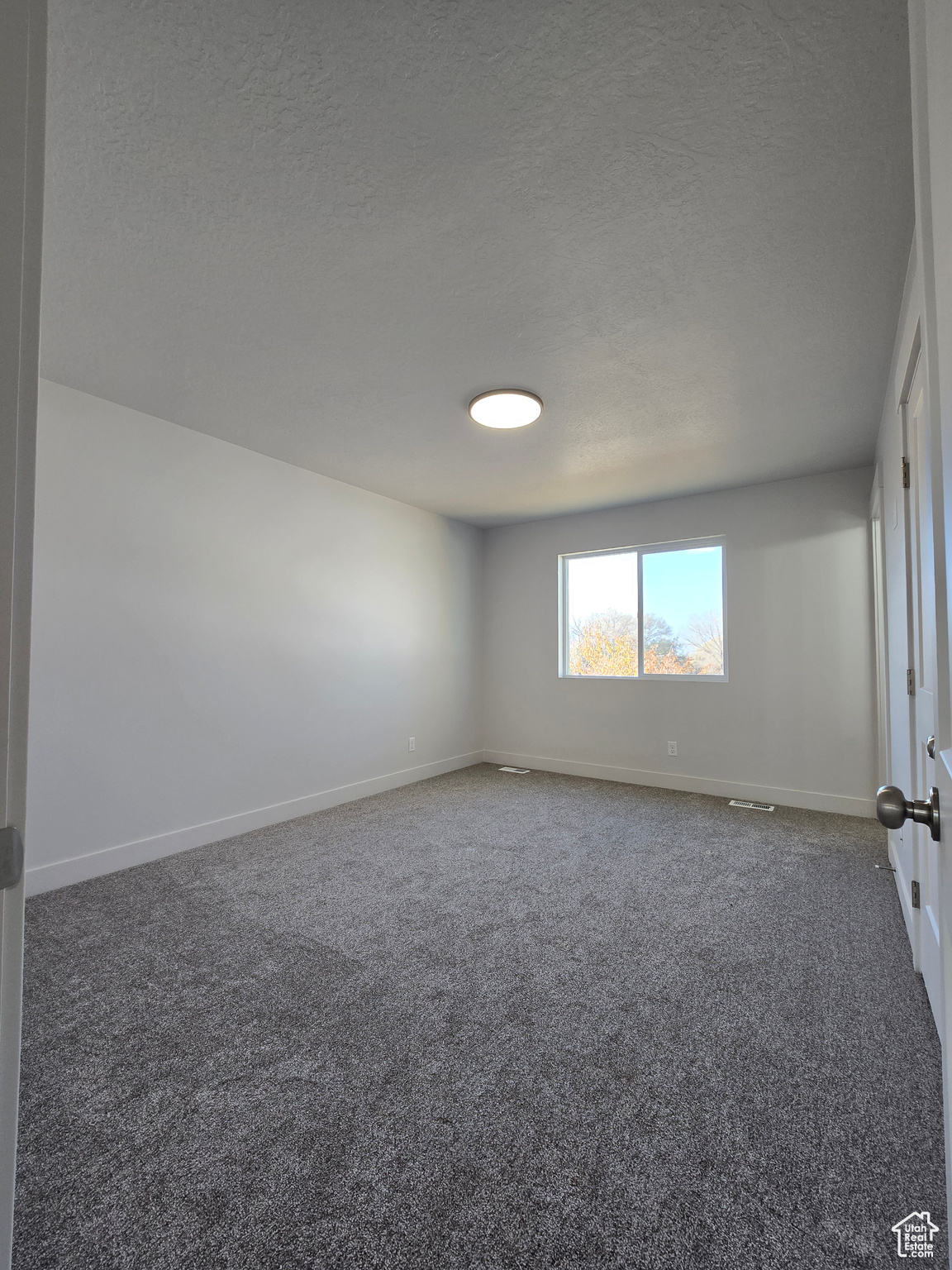 Carpeted empty room with a textured ceiling