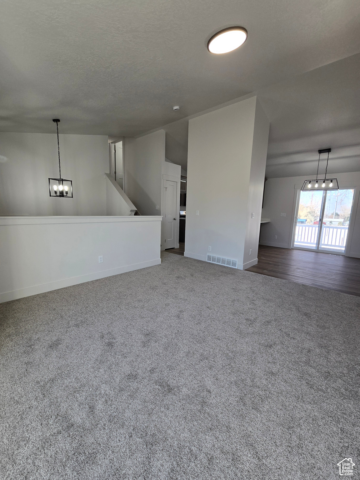 Unfurnished living room with carpet flooring and a textured ceiling