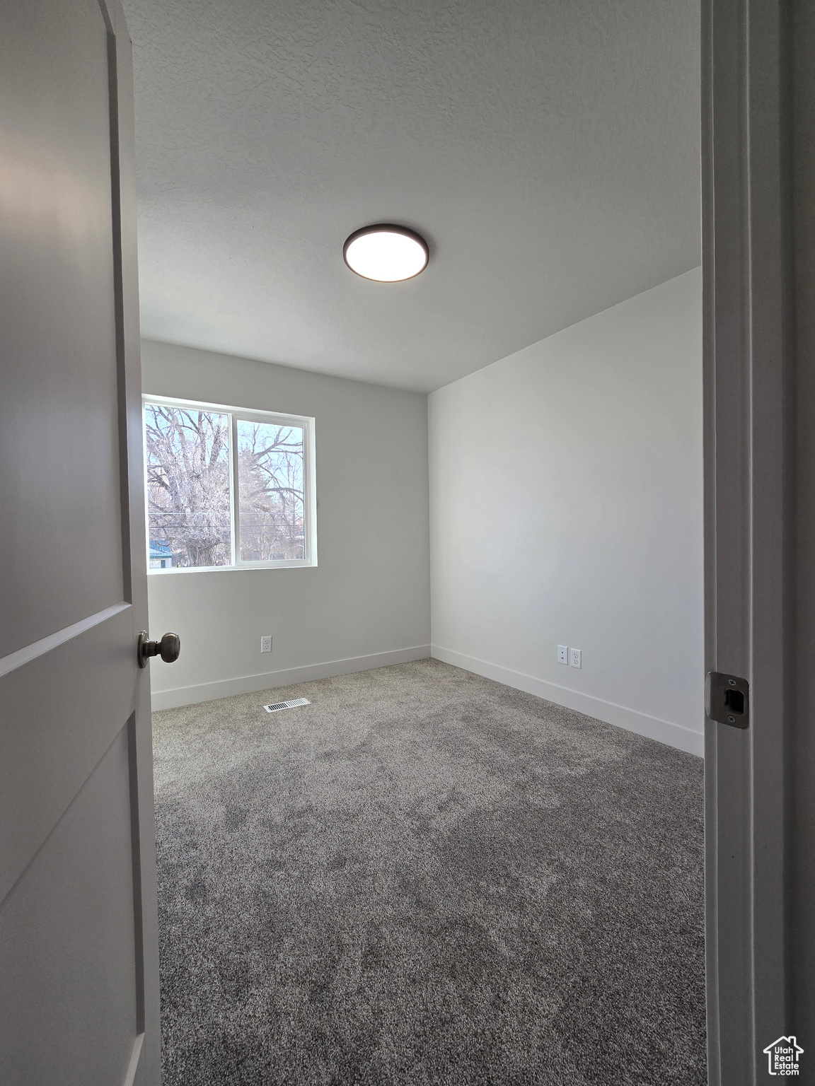 Empty room with carpet and a textured ceiling