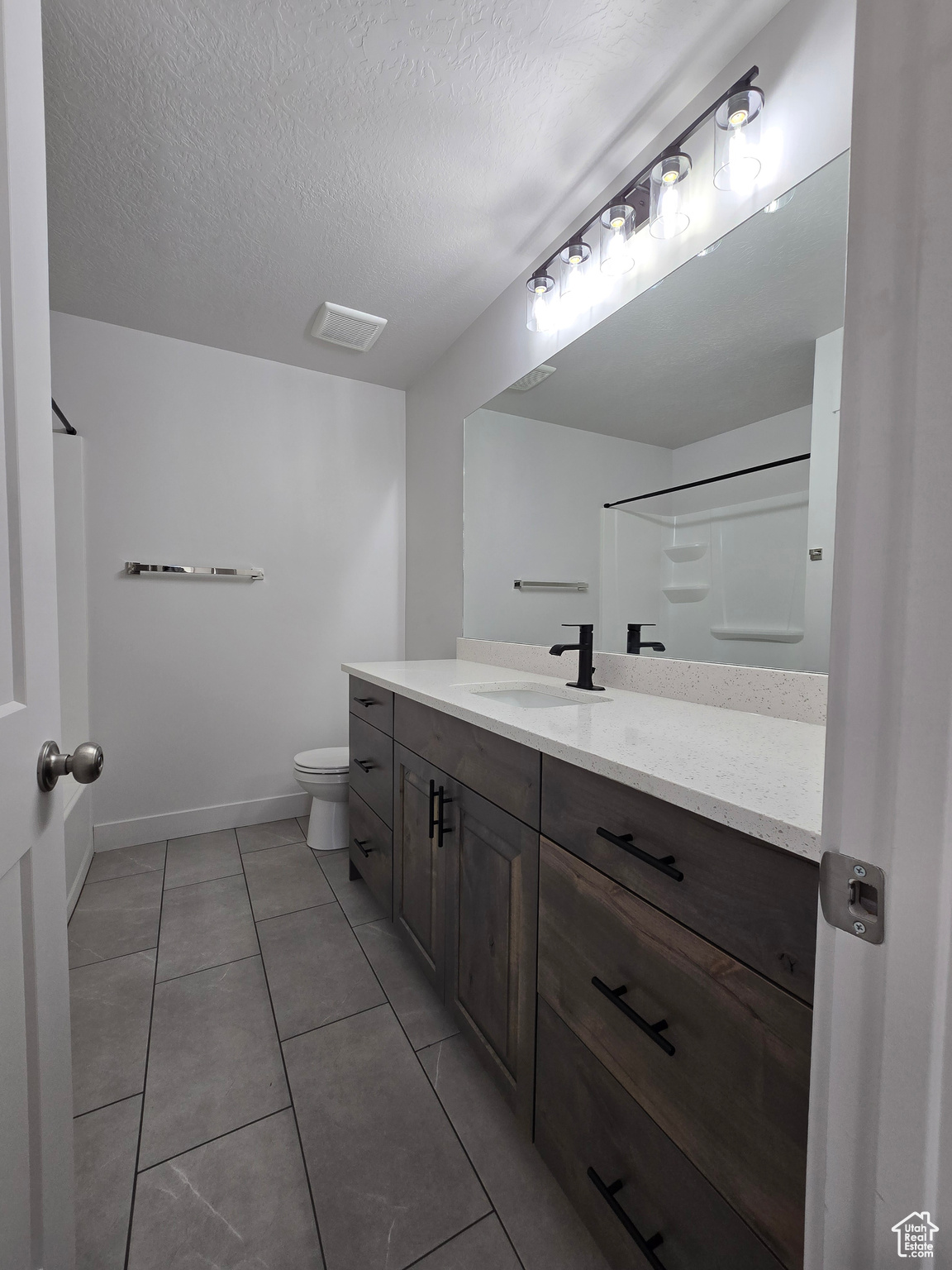 Bathroom featuring vanity, a textured ceiling, toilet, and tile patterned flooring