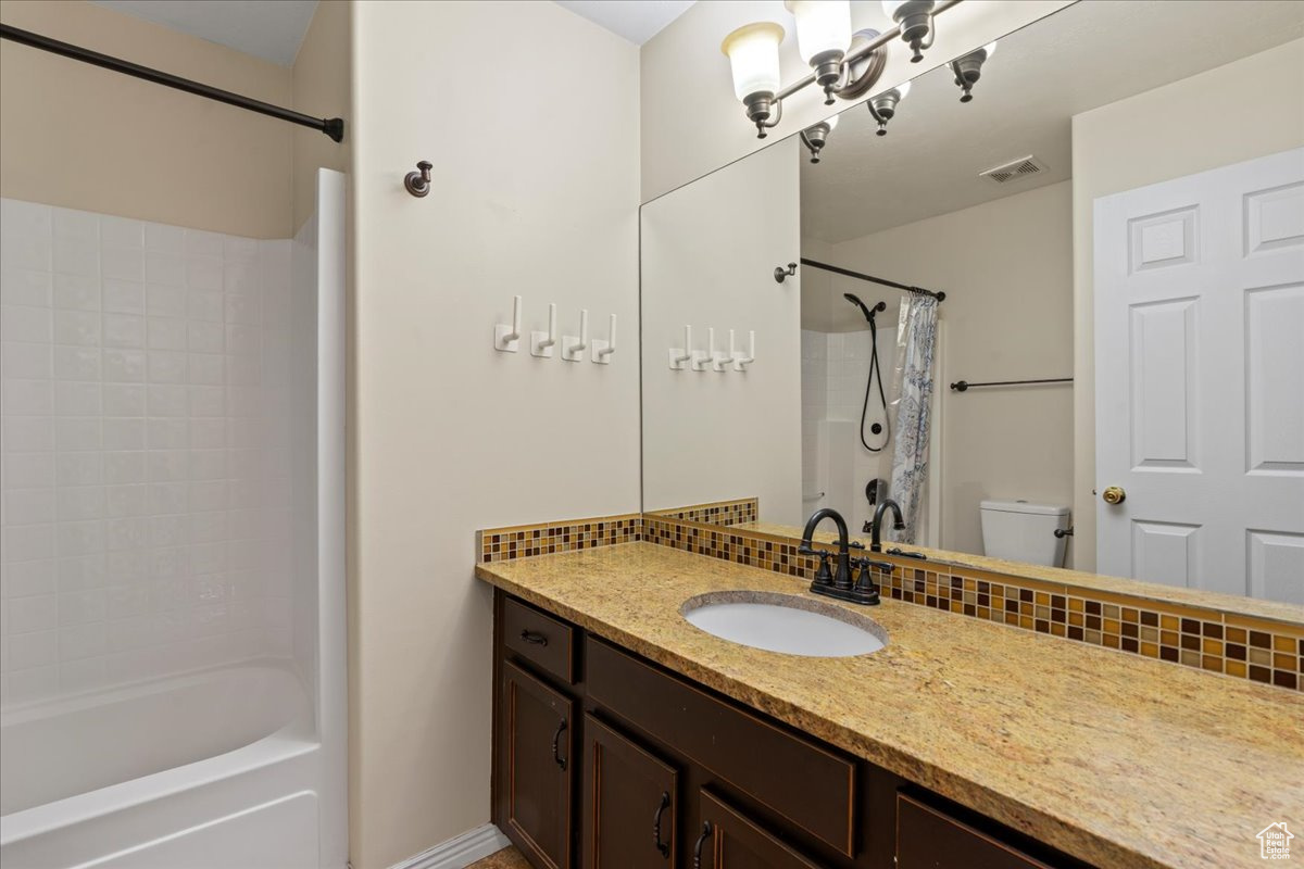 Full bathroom featuring shower / tub combo with curtain, vanity, and toilet