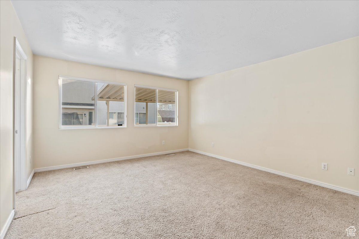 Empty room featuring a textured ceiling and light colored carpet