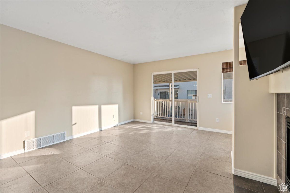 Unfurnished living room featuring a tile fireplace and light tile patterned flooring