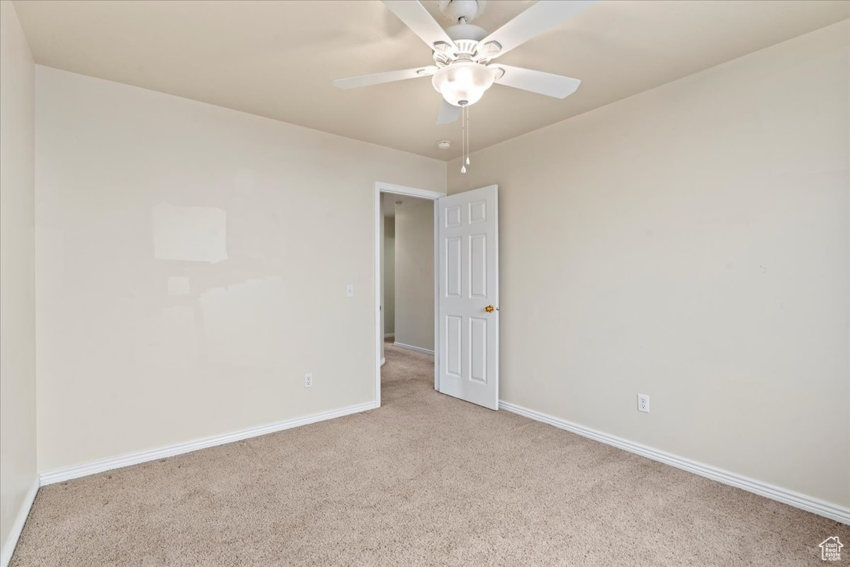 Spare room featuring light carpet and ceiling fan