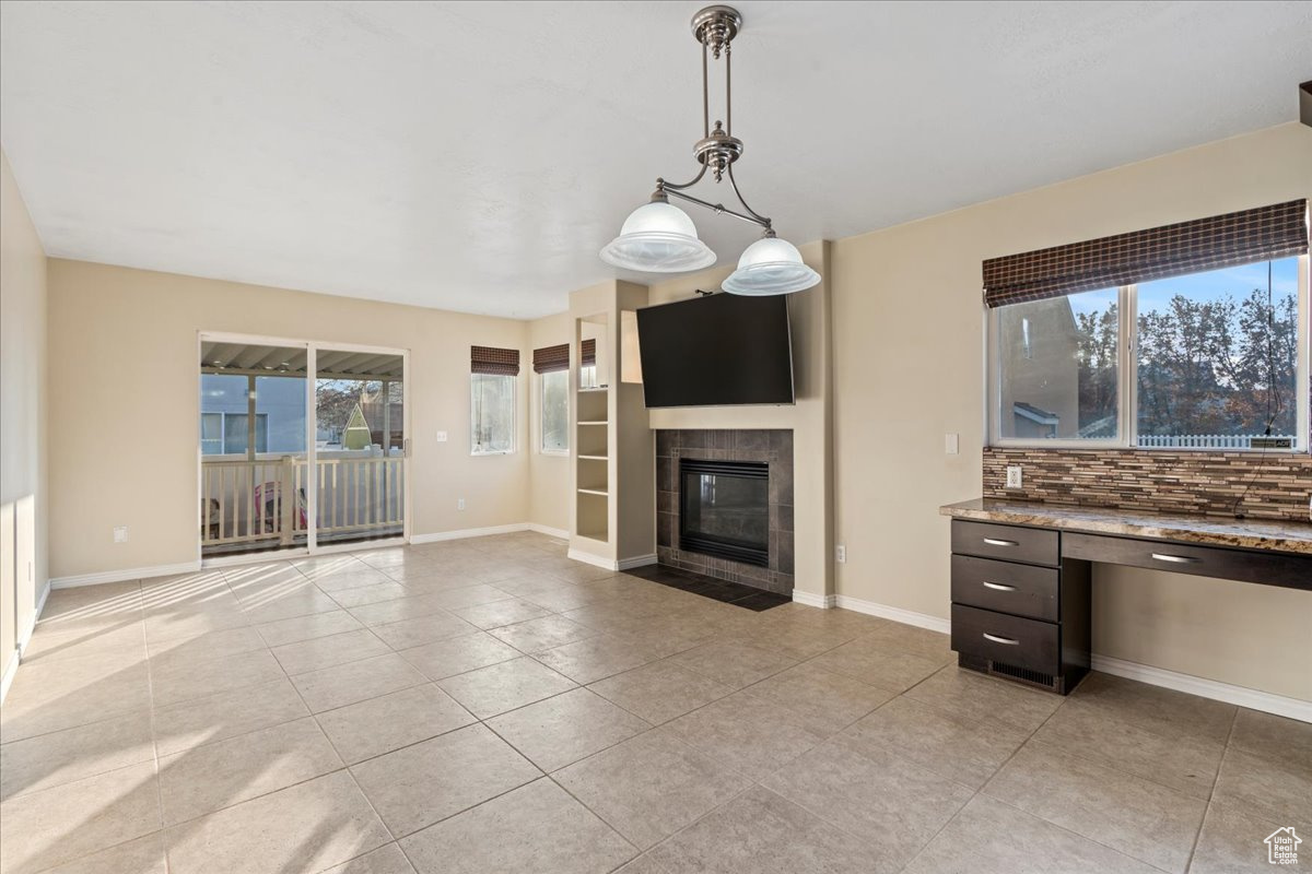 Unfurnished living room featuring a tile fireplace and light tile patterned floors