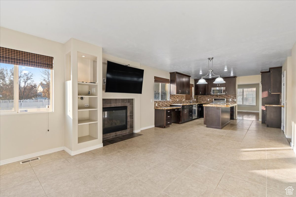 Kitchen featuring a wealth of natural light, a center island, pendant lighting, and dark brown cabinets