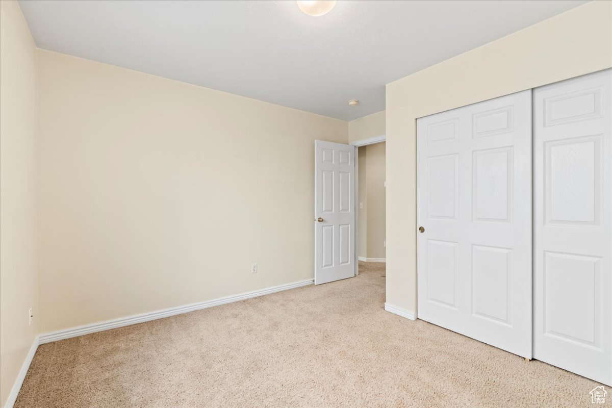 Unfurnished bedroom with light colored carpet and a closet