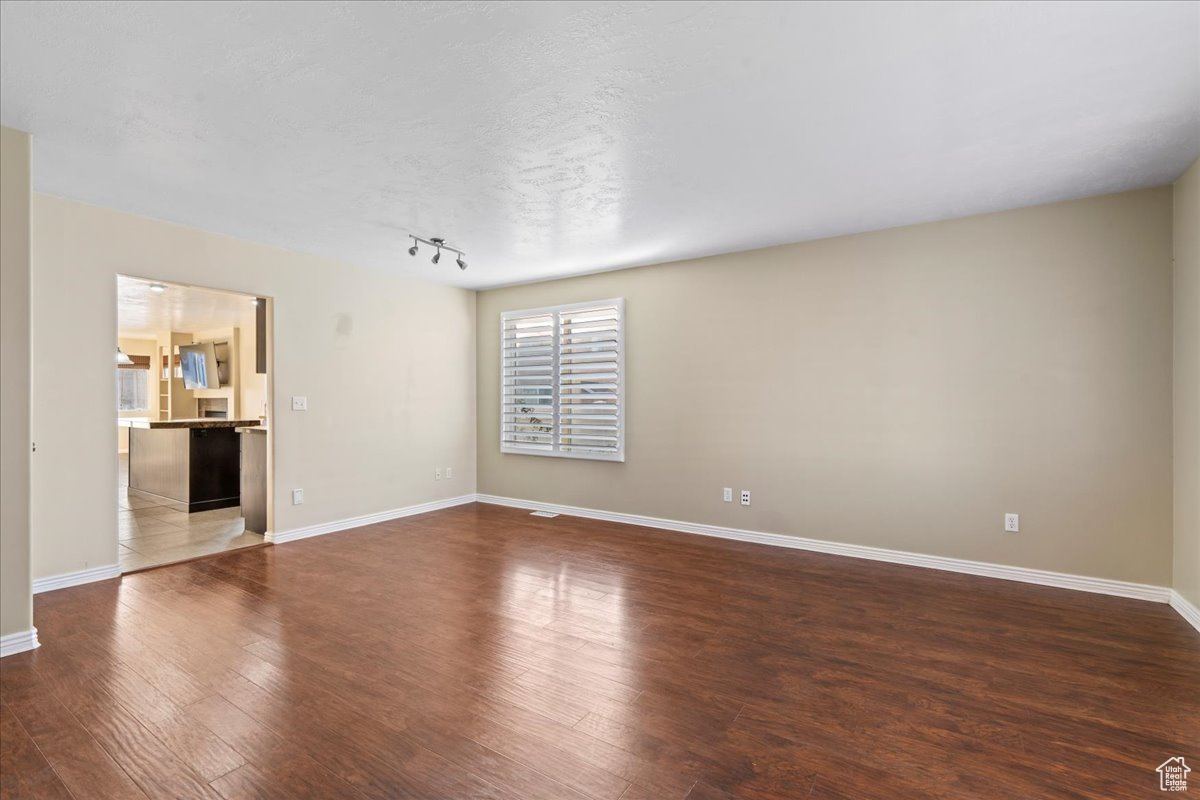 Unfurnished room with dark hardwood / wood-style flooring and a textured ceiling