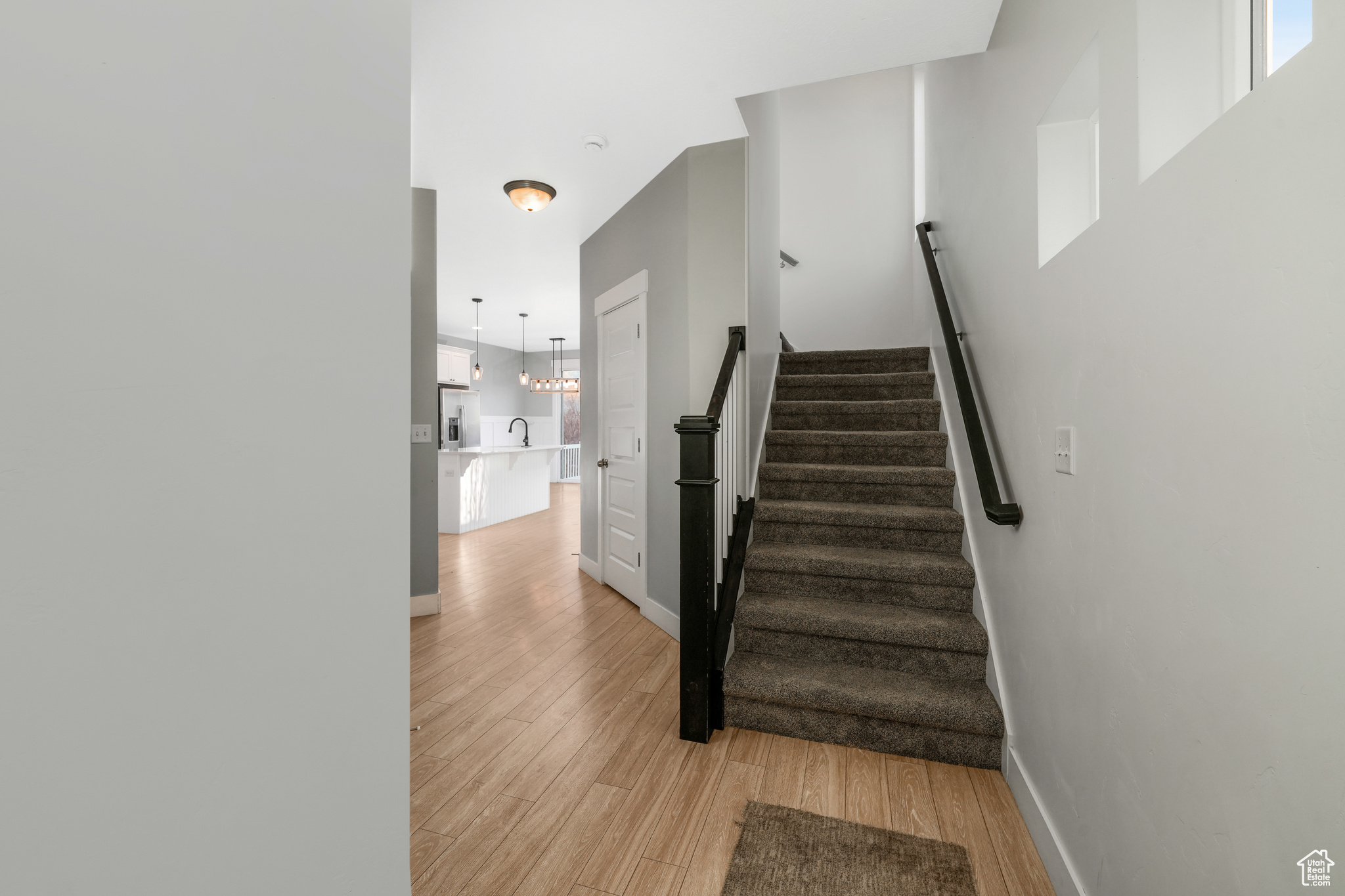 Stairway featuring wood-type flooring, sink, and an inviting chandelier