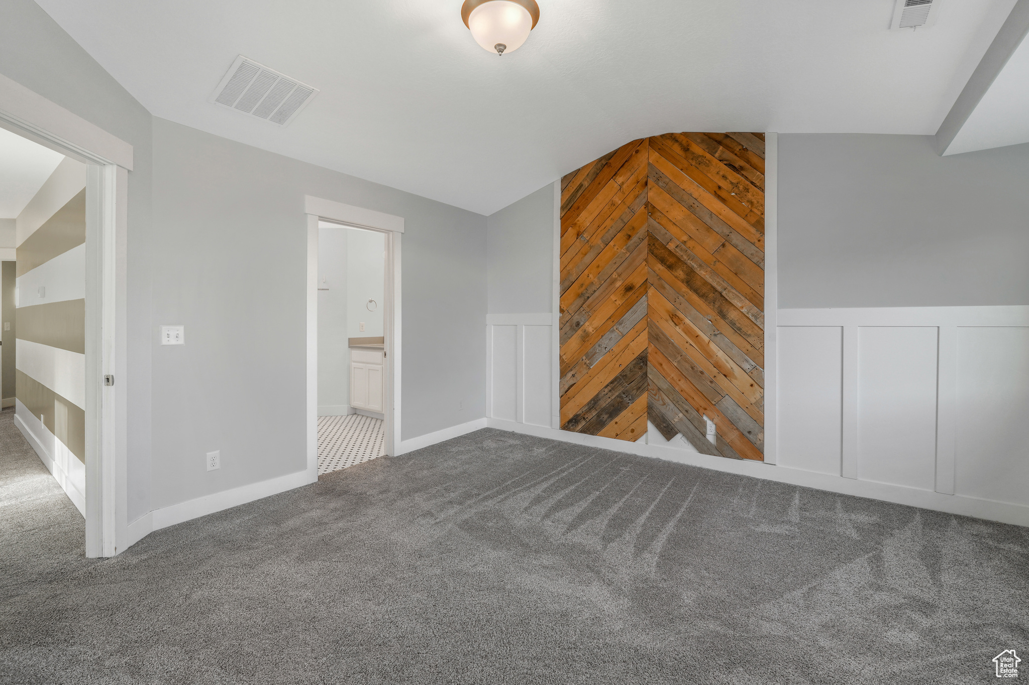 Unfurnished living room with carpet flooring, wood walls, and lofted ceiling