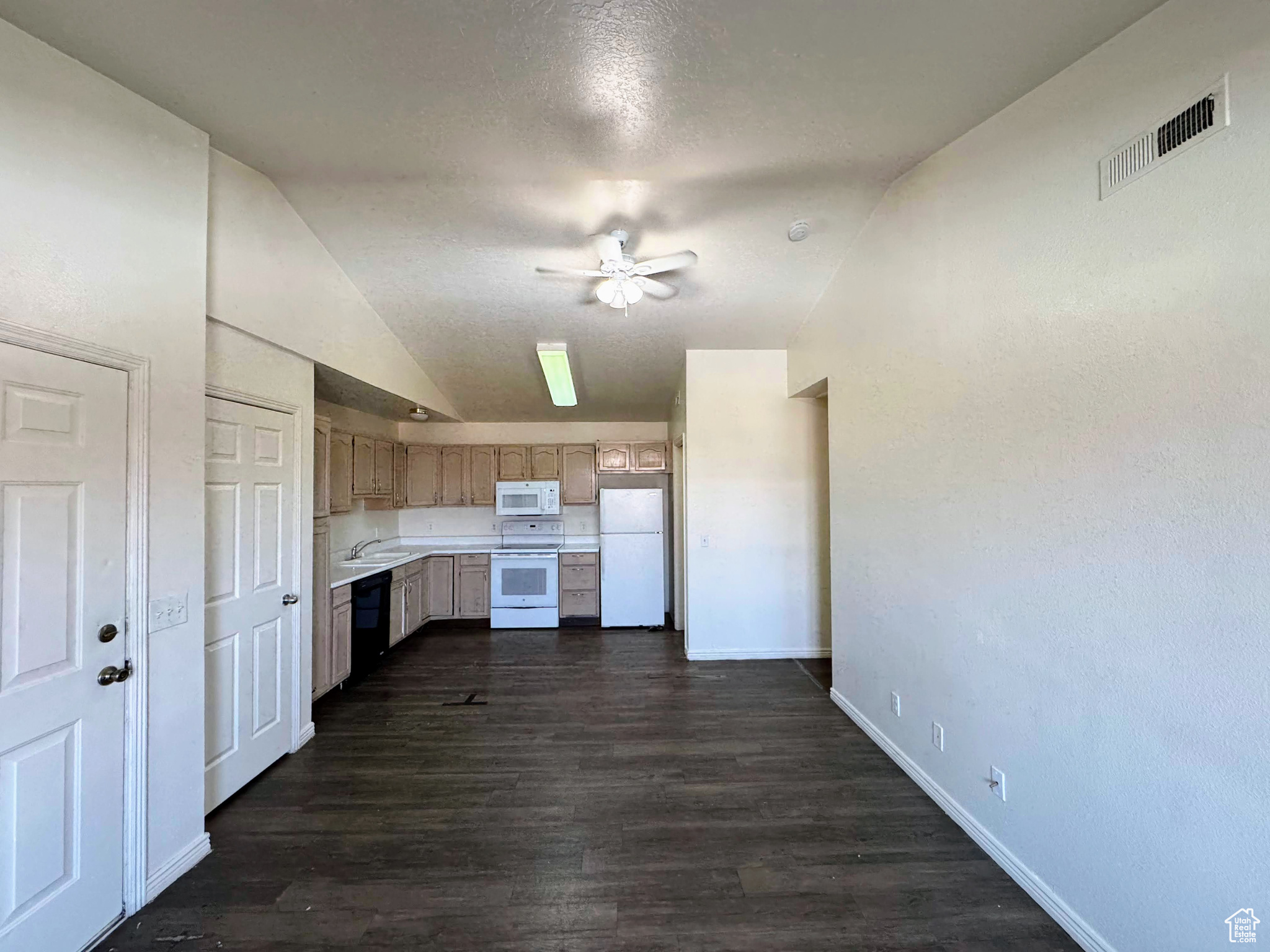 Kitchen with lofted ceiling, white appliances, sink, dark hardwood / wood-style floors, and ceiling fan