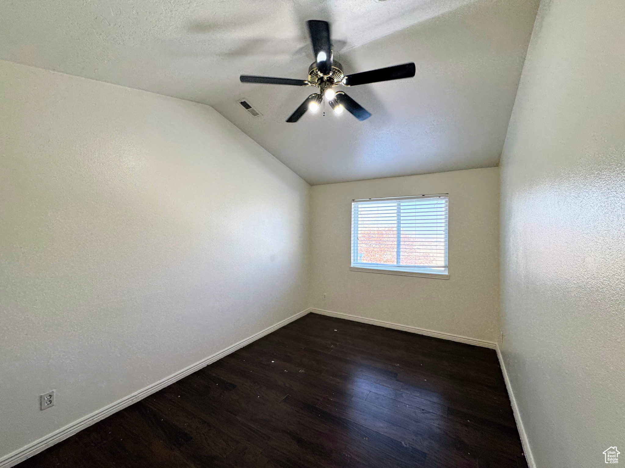 Empty room featuring ceiling fan, dark hardwood / wood-style flooring, and lofted ceiling