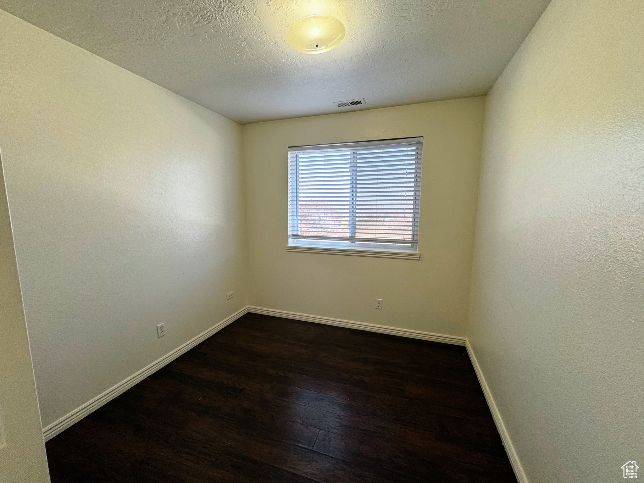 Spare room featuring dark hardwood / wood-style flooring and a textured ceiling