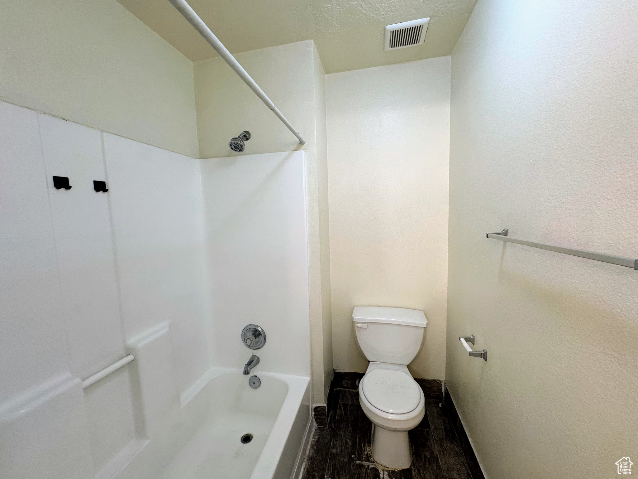 Bathroom featuring hardwood / wood-style floors, a textured ceiling, toilet, and tub / shower combination