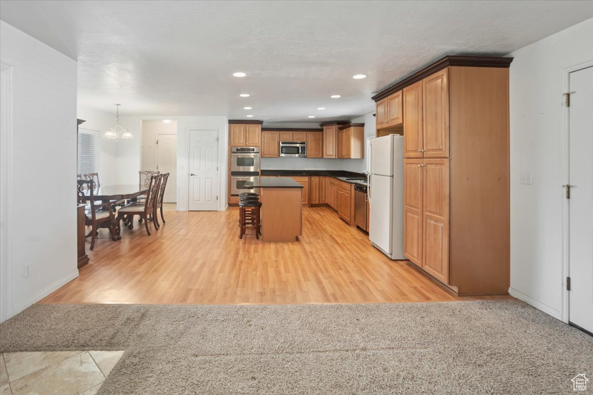 Kitchen with granite countertops, stainless steel appliances, light hardwood / wood-style floors, and a kitchen island