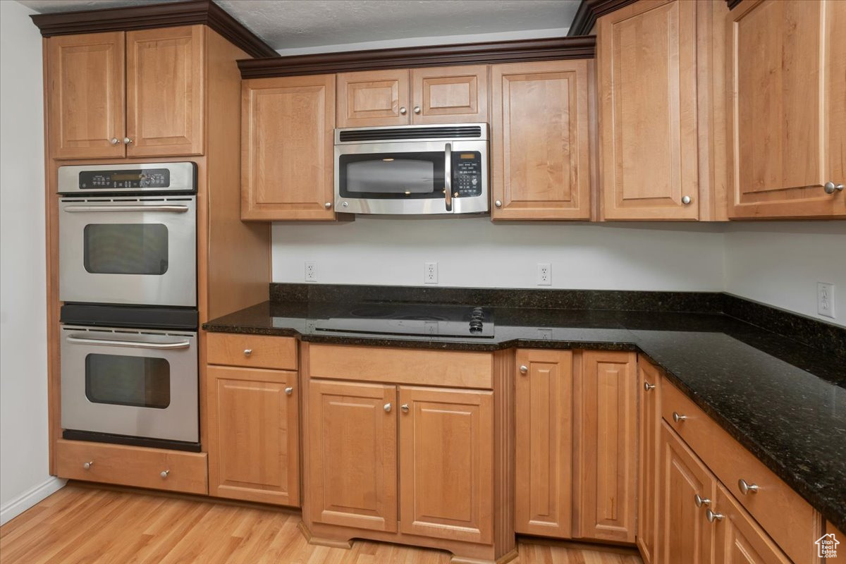 Kitchen with granite countertops, stainless steel appliances, light hardwood / wood-style floors, and a kitchen island