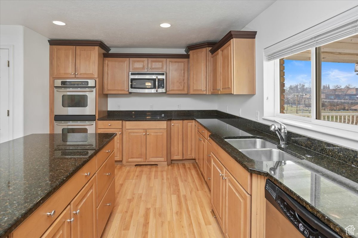 Kitchen with granite countertops, stainless steel appliances, light hardwood / wood-style floors, and a kitchen island