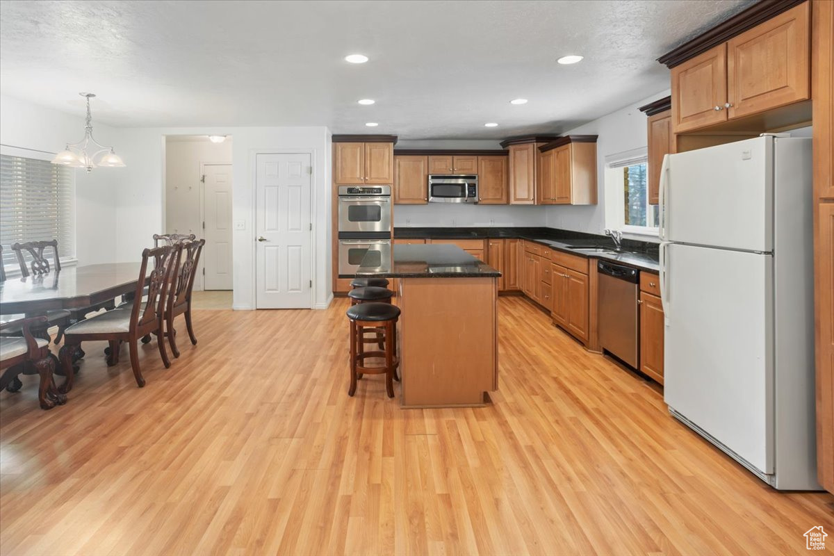 Kitchen with granite countertops, stainless steel appliances, light hardwood / wood-style floors, and a kitchen island