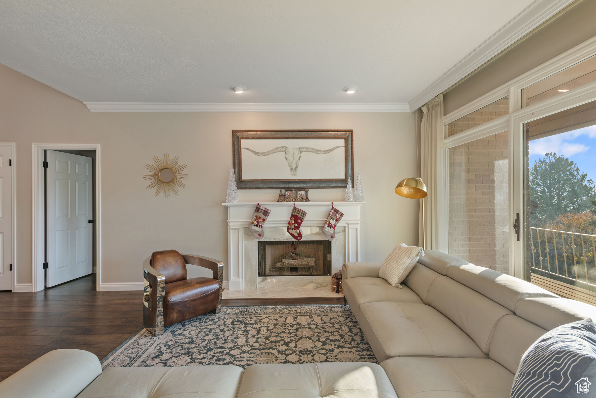 Living room featuring a fireplace, hardwood / wood-style flooring, crown molding, and a healthy amount of sunlight