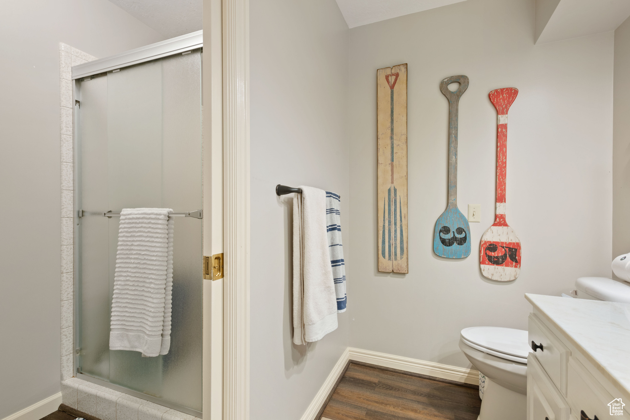 Bathroom with hardwood / wood-style floors, vanity, an enclosed shower, and toilet