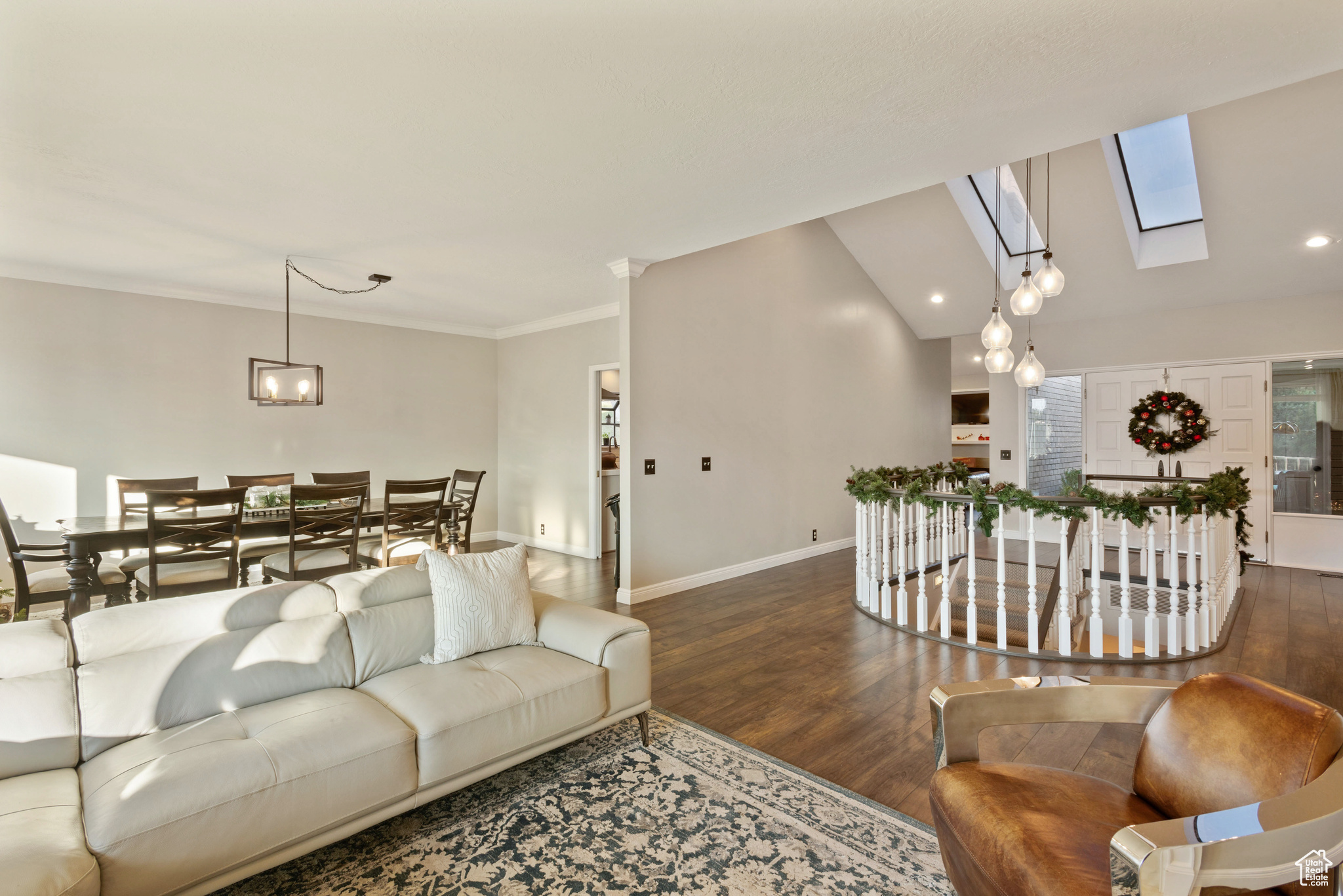 Living room featuring crown molding, vaulted ceiling with skylight, and dark wood-type flooring