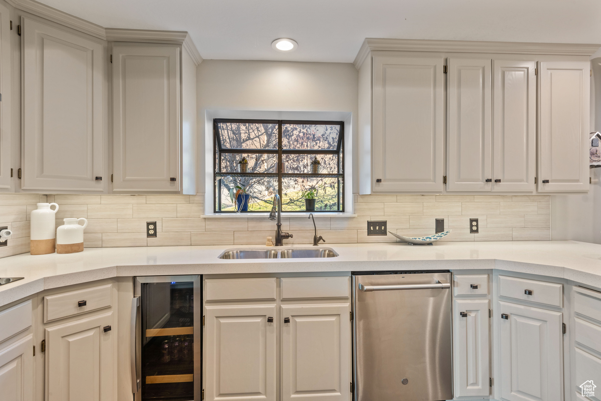 Kitchen with wine cooler, white cabinetry, sink, and decorative backsplash