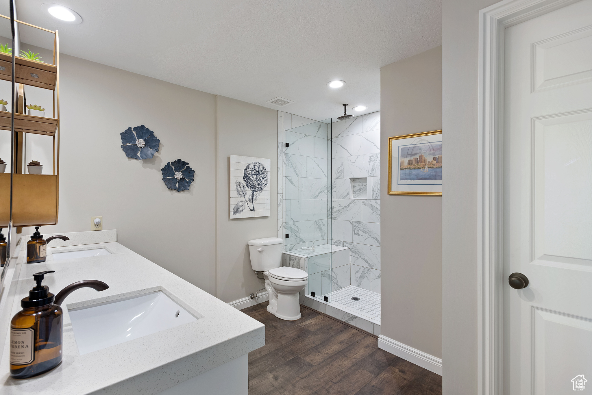 Bathroom featuring toilet, vanity, wood-type flooring, and tiled shower