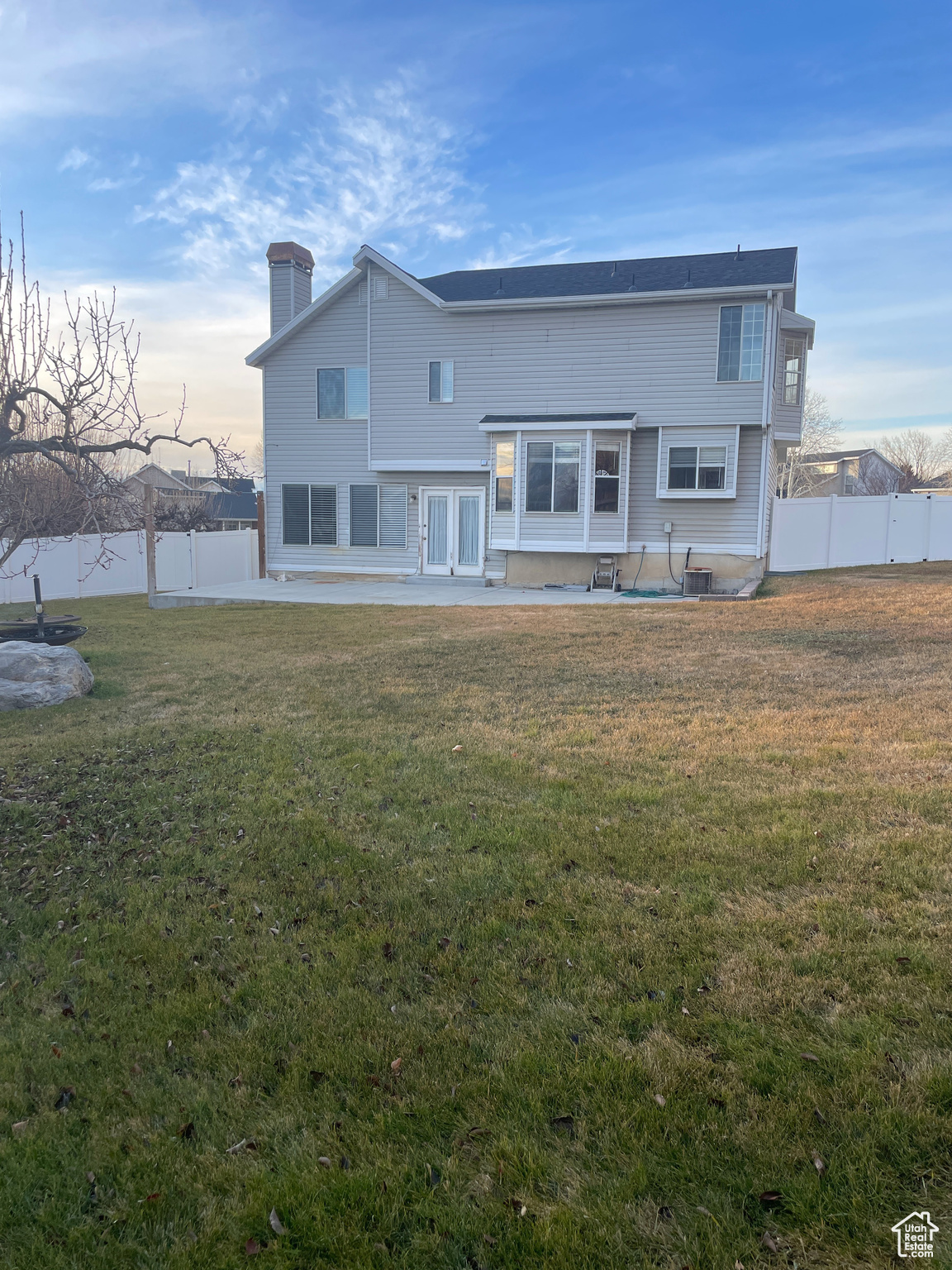 Back house at dusk with a patio area and a lawn