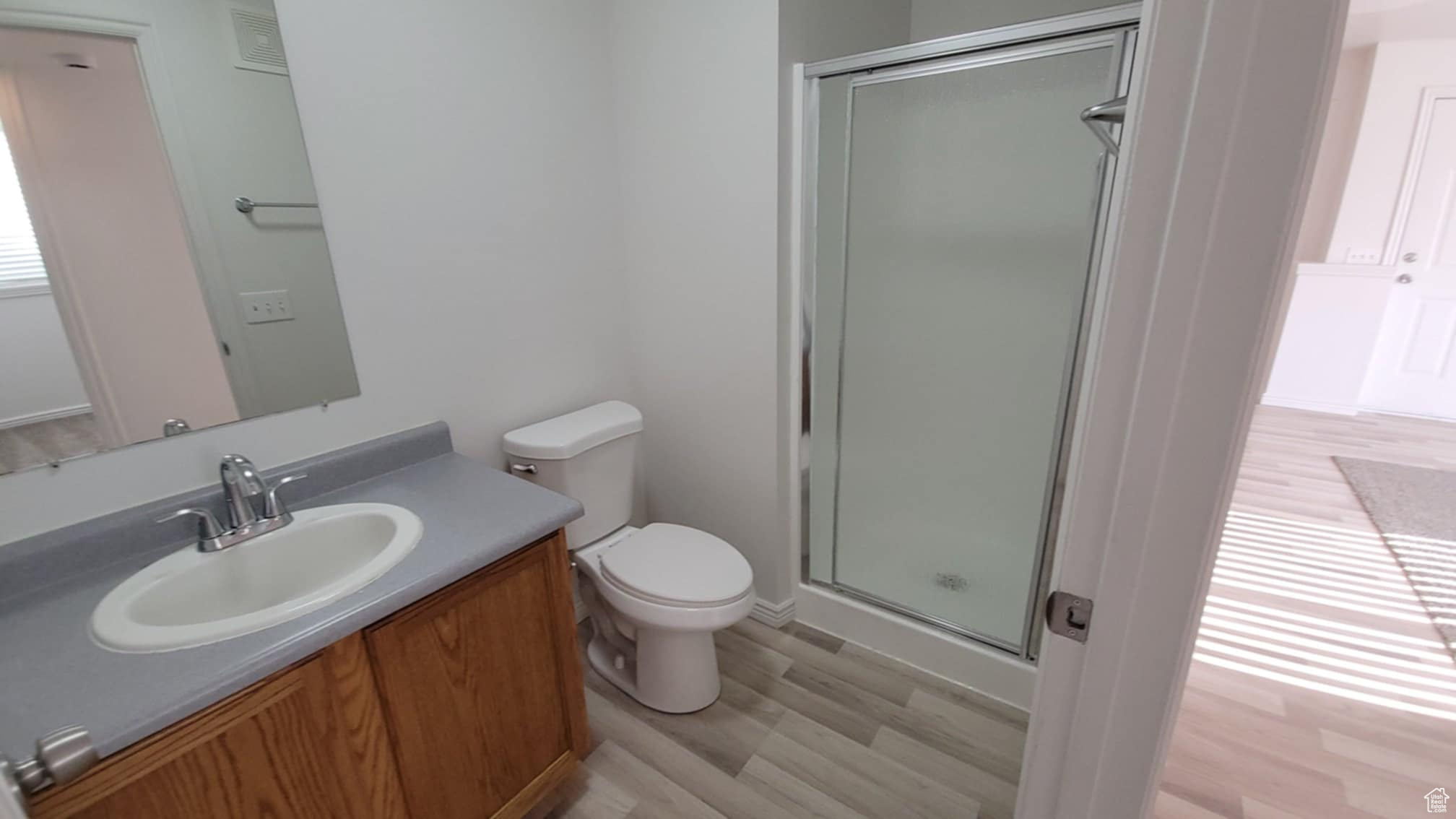 Bathroom featuring vanity, hardwood / wood-style flooring, toilet, and a shower with door