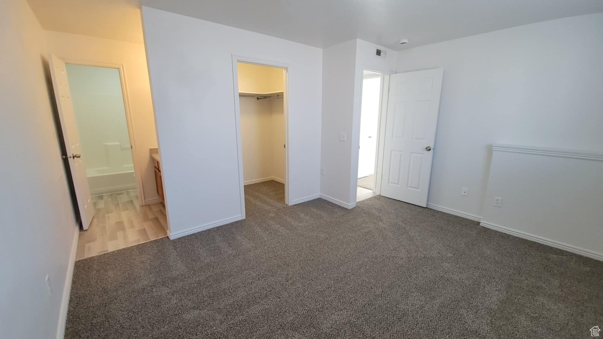 Unfurnished bedroom featuring connected bathroom, a spacious closet, a closet, and carpet floors