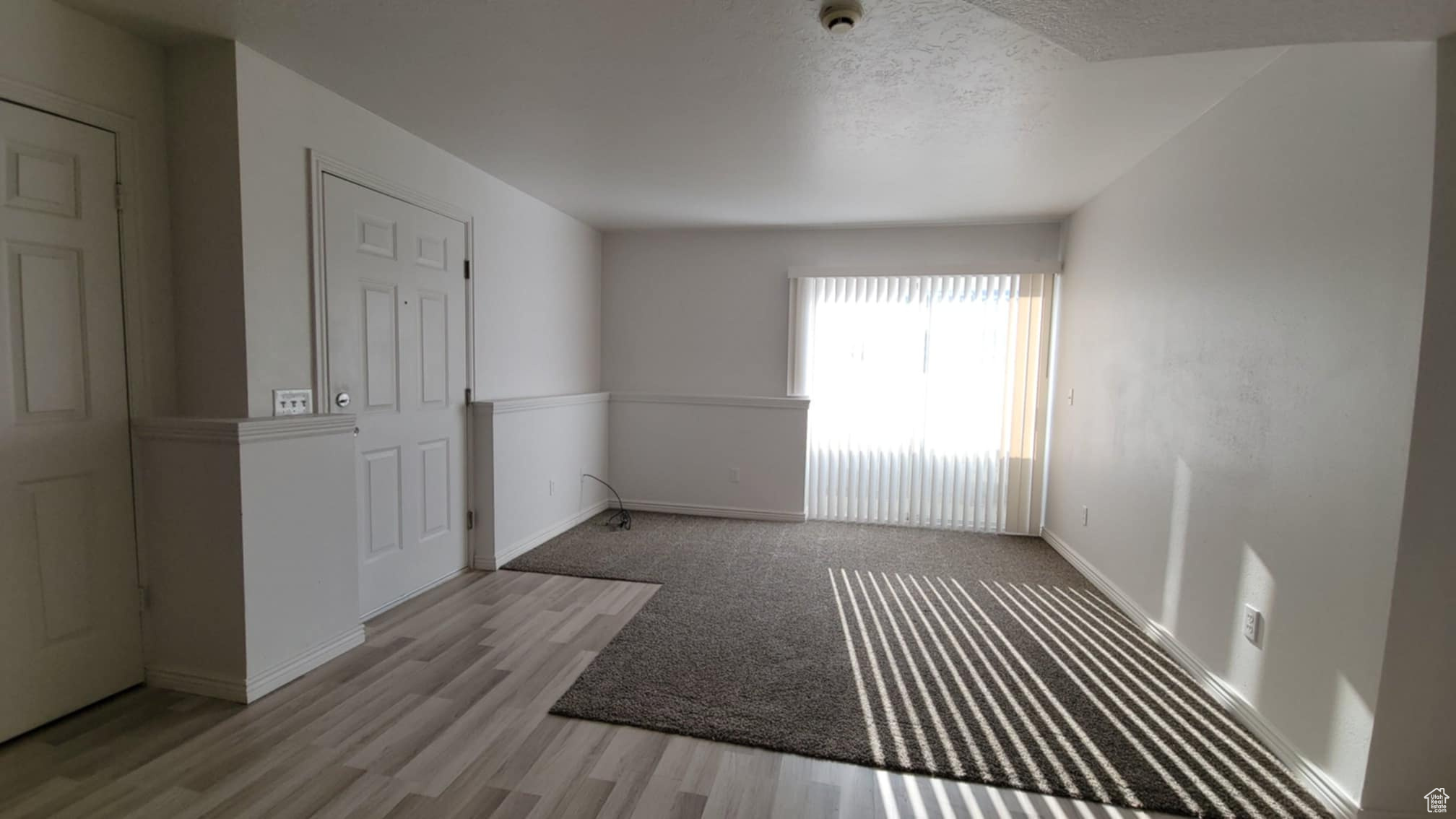 Empty room with a textured ceiling and light hardwood / wood-style flooring