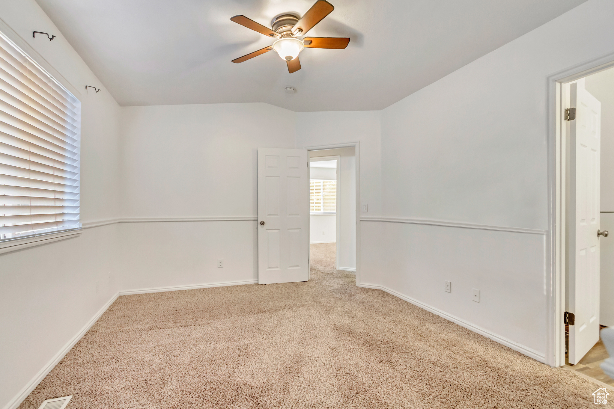 Spare room featuring ceiling fan, lofted ceiling, and light carpet