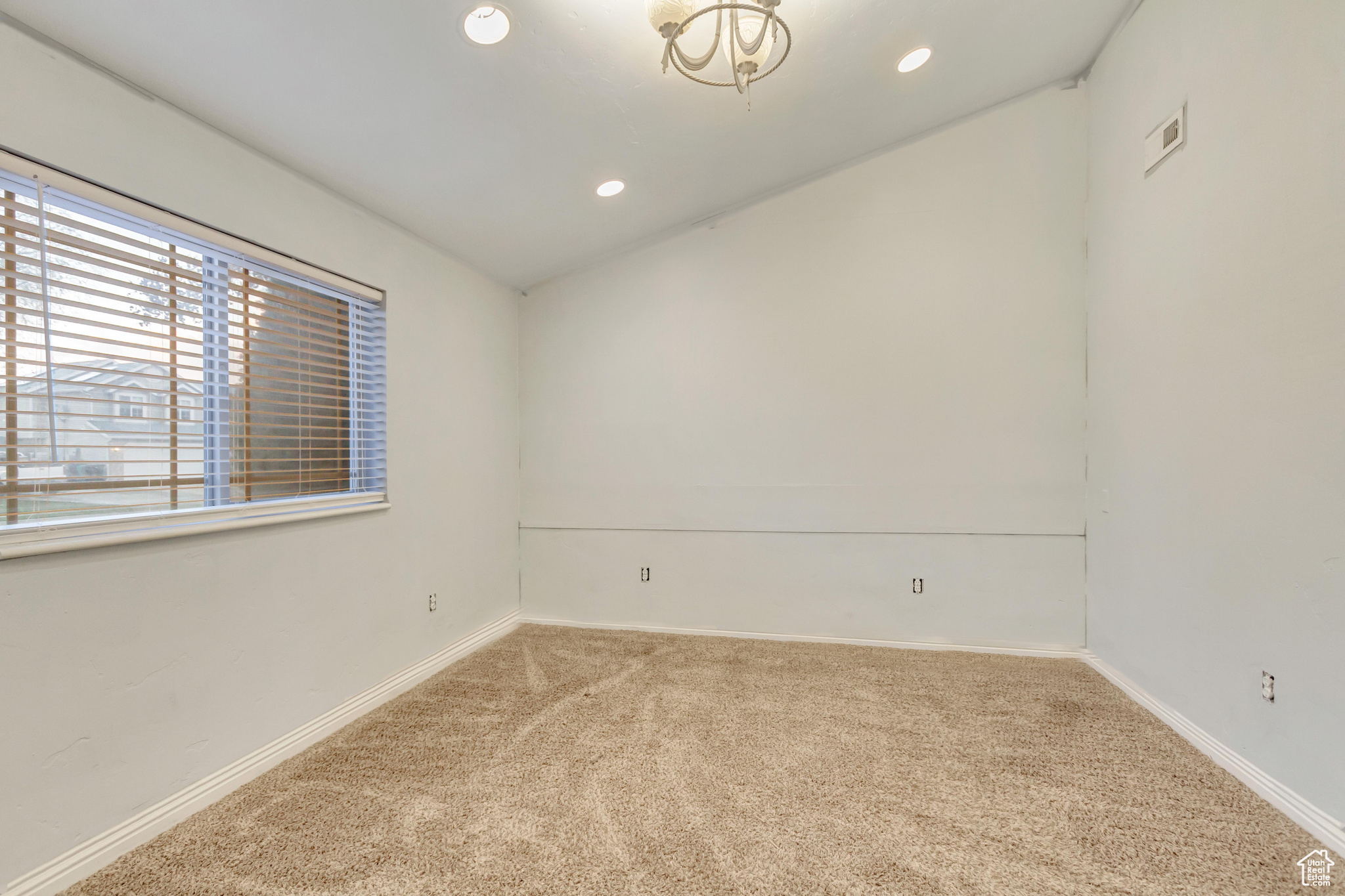 Carpeted spare room featuring vaulted ceiling