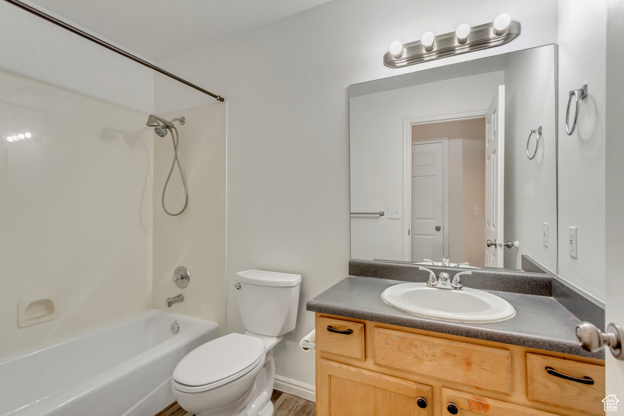 Full bathroom with shower / tub combination, vanity, toilet, and hardwood / wood-style floors