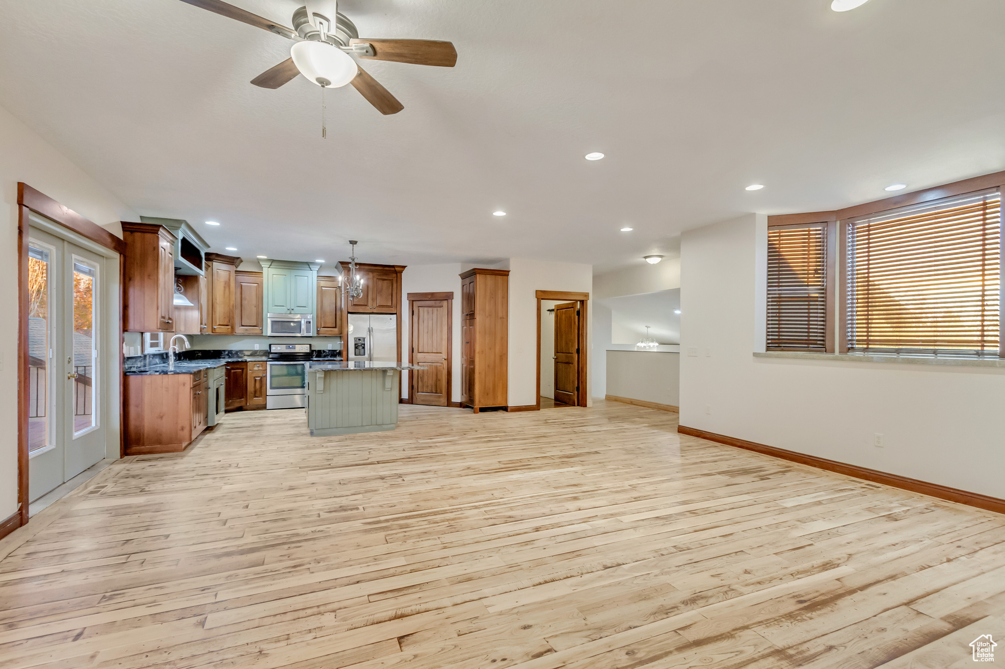 Kitchen with pendant lighting, a center island, light hardwood / wood-style flooring, ceiling fan, and appliances with stainless steel finishes