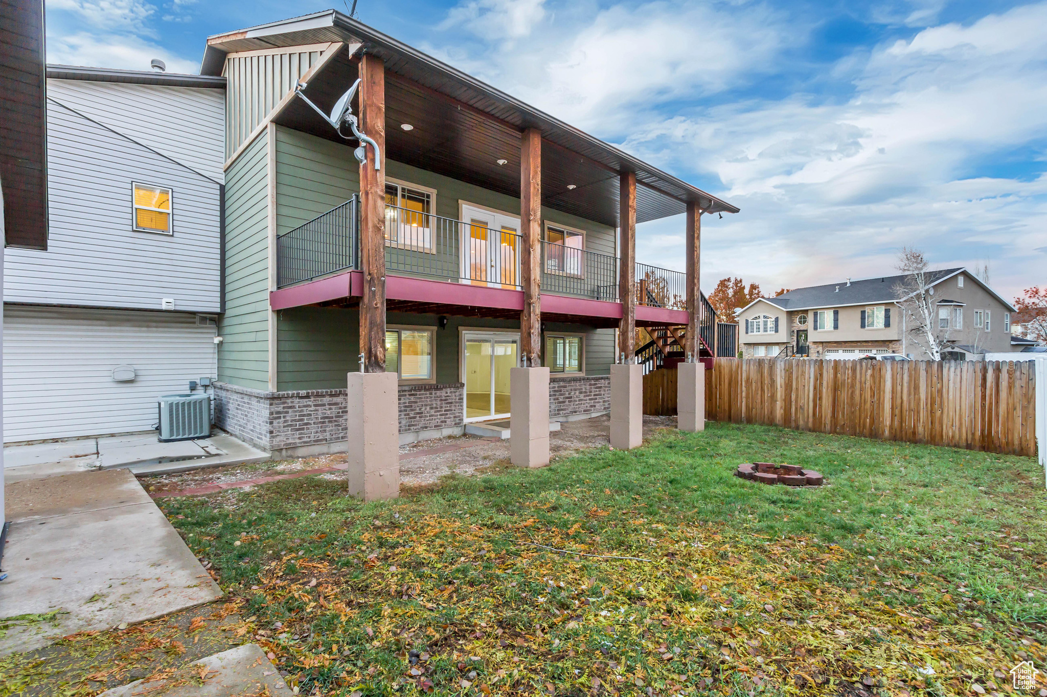 Back of house featuring a balcony, a yard, an outdoor fire pit, and central AC