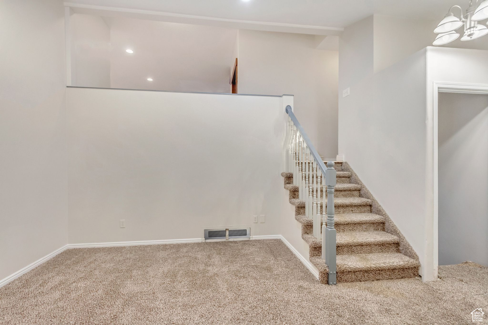 Stairway with carpet and an inviting chandelier