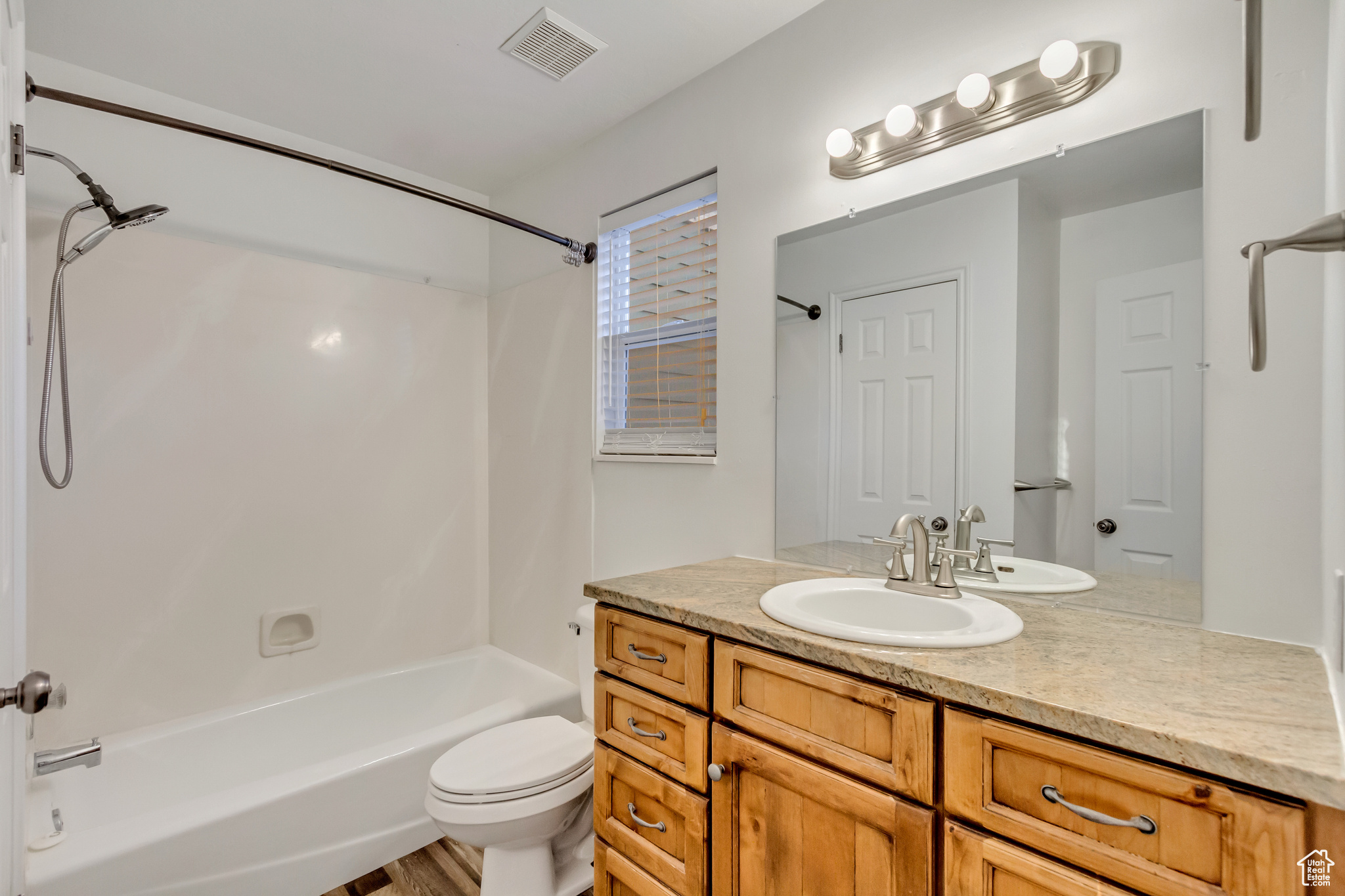 Full bathroom with toilet, vanity, bathtub / shower combination, and hardwood / wood-style flooring