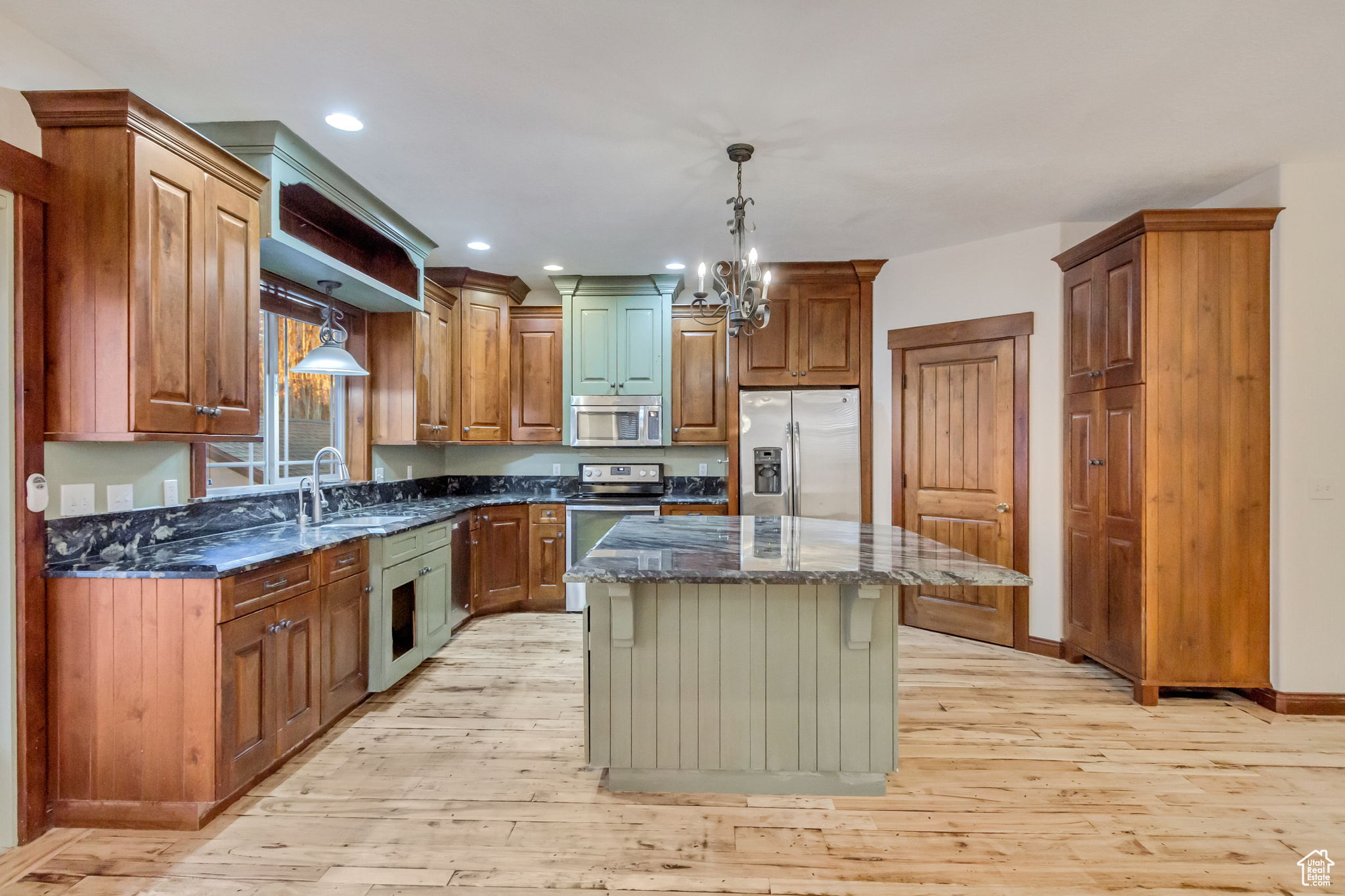 Kitchen featuring dark stone counters, a center island, stainless steel appliances, and light hardwood / wood-style floors