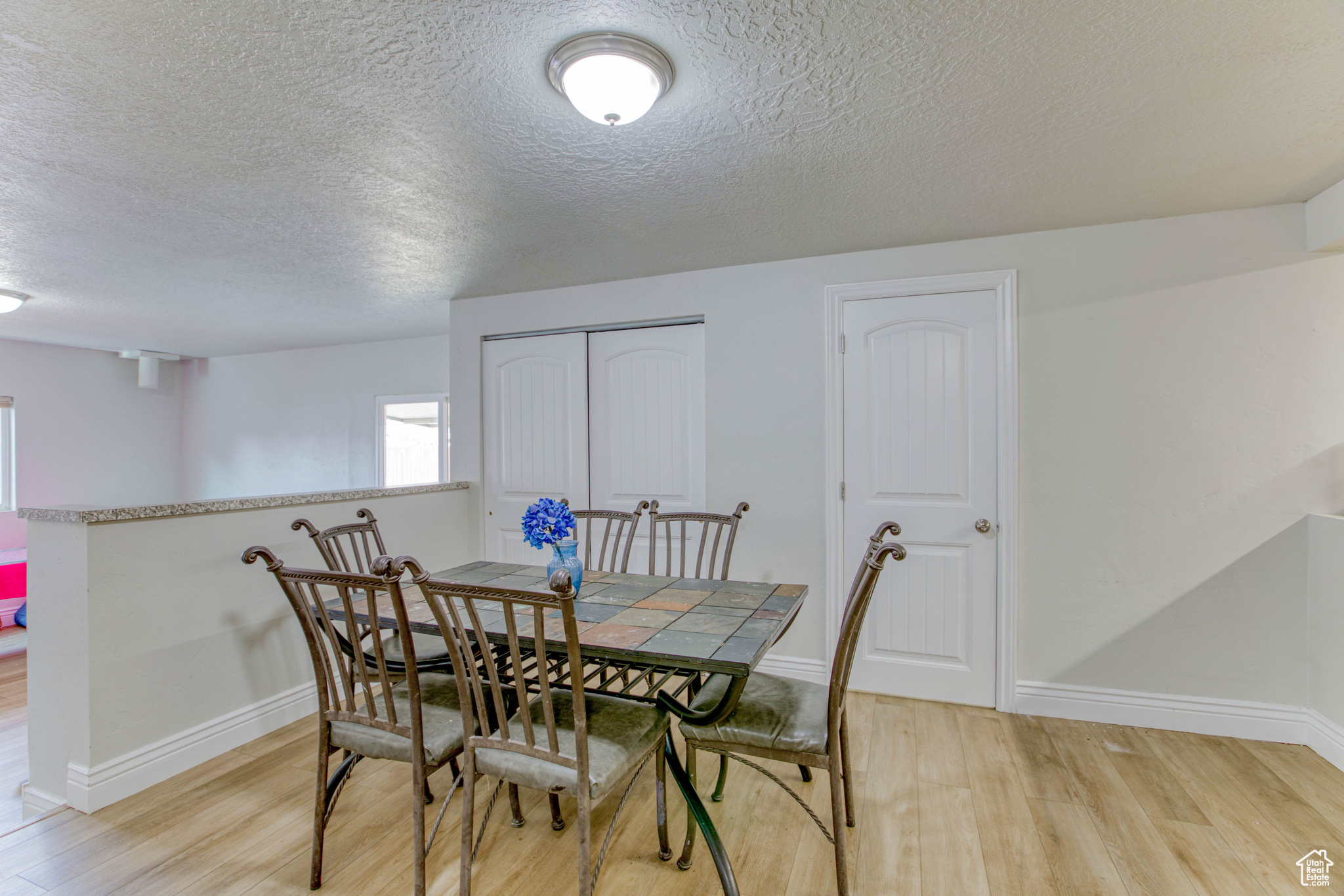 Dining space with light hardwood / wood-style flooring and a textured ceiling