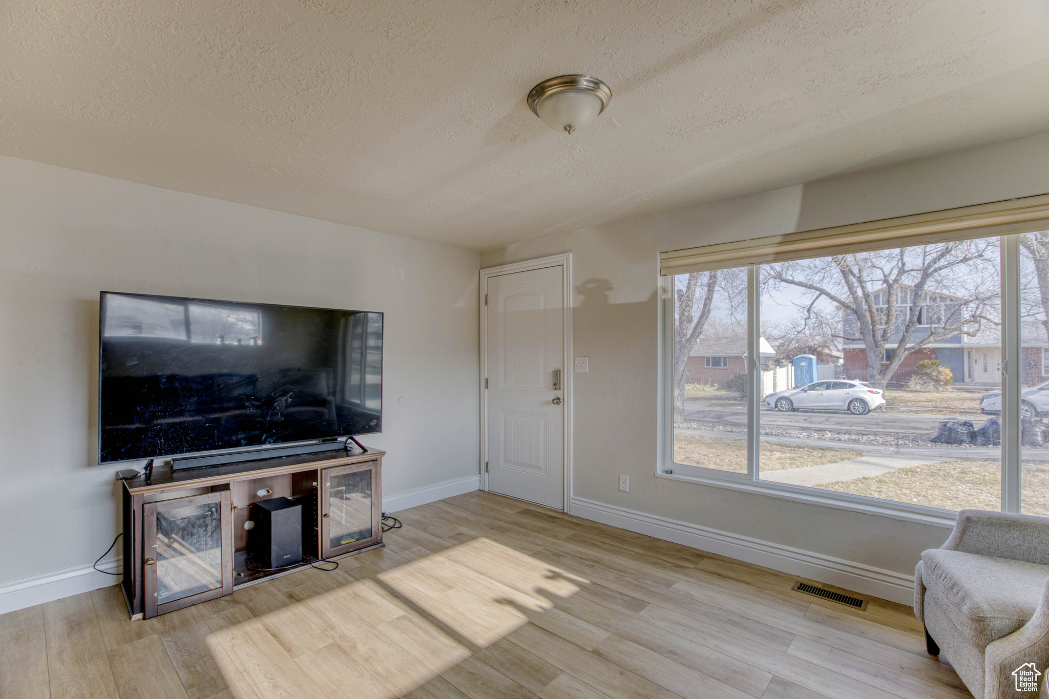 Living room featuring a textured ceiling and light hardwood / wood-style flooring