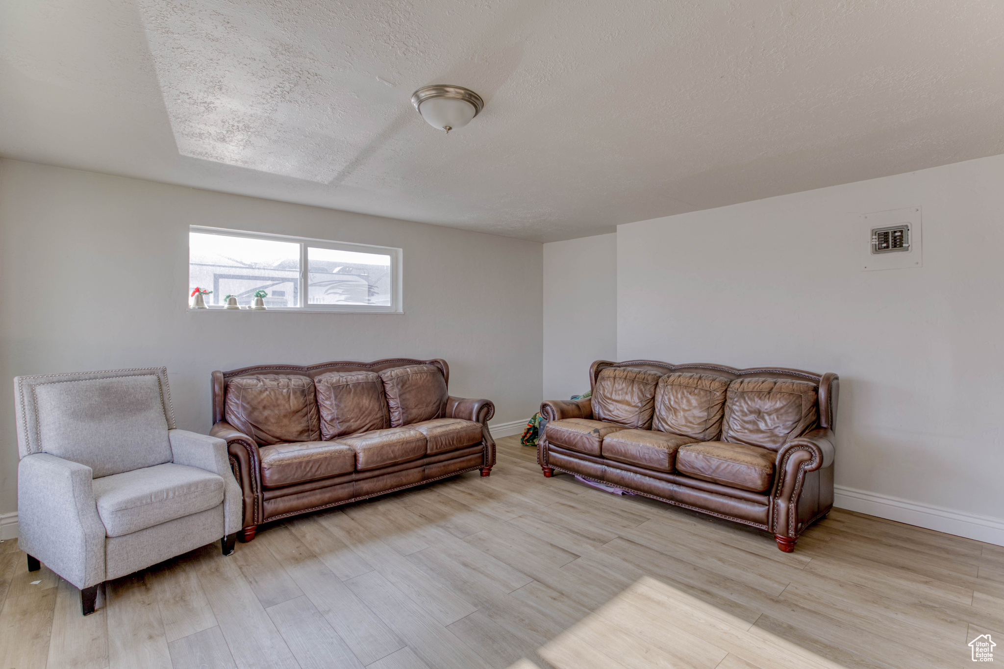 Living room with a textured ceiling and light hardwood / wood-style flooring