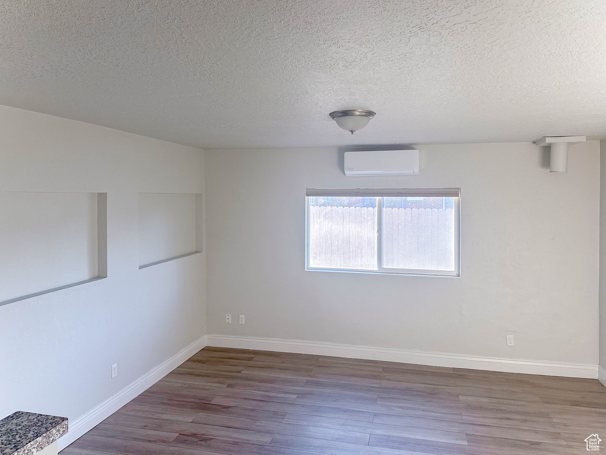 Spare room with mini split unit, dark wood-type flooring, and a textured ceiling