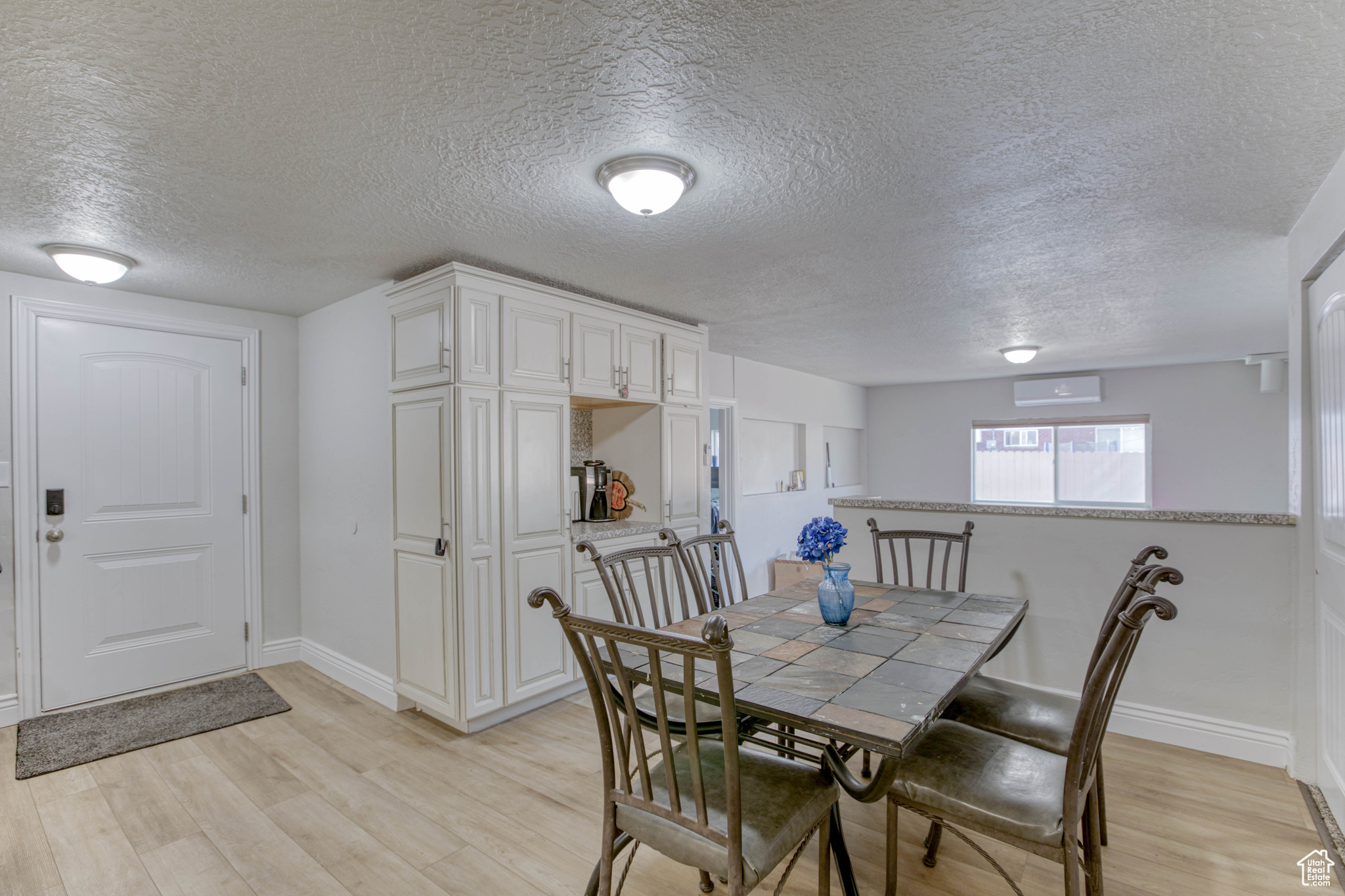 Dining room with a textured ceiling, light hardwood / wood-style flooring, and a wall unit AC