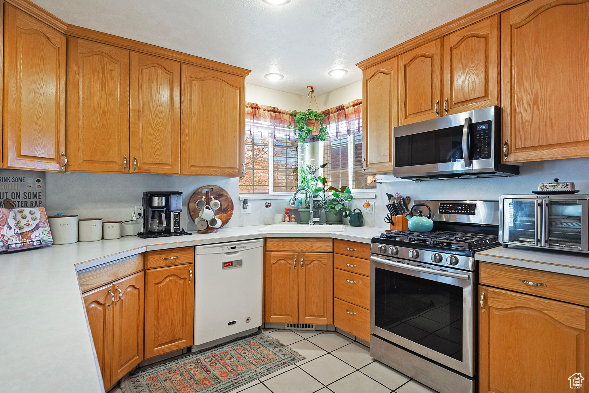 Kitchen featuring light tile patterned floors, sink, and appliances with stainless steel finishes