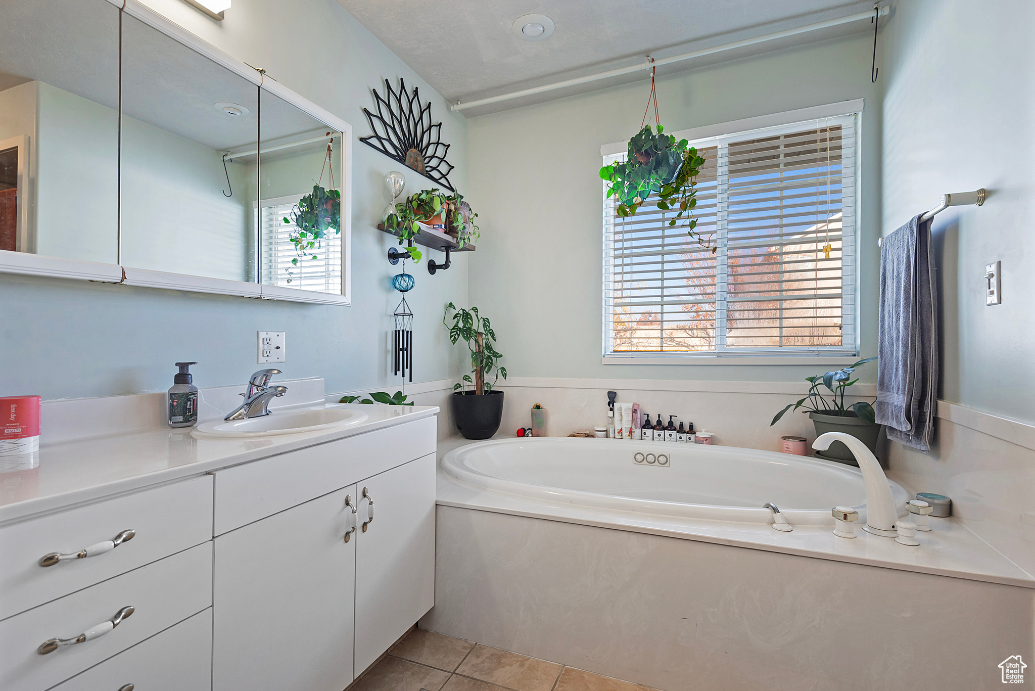 Bathroom featuring tile patterned floors, vanity, and a bath