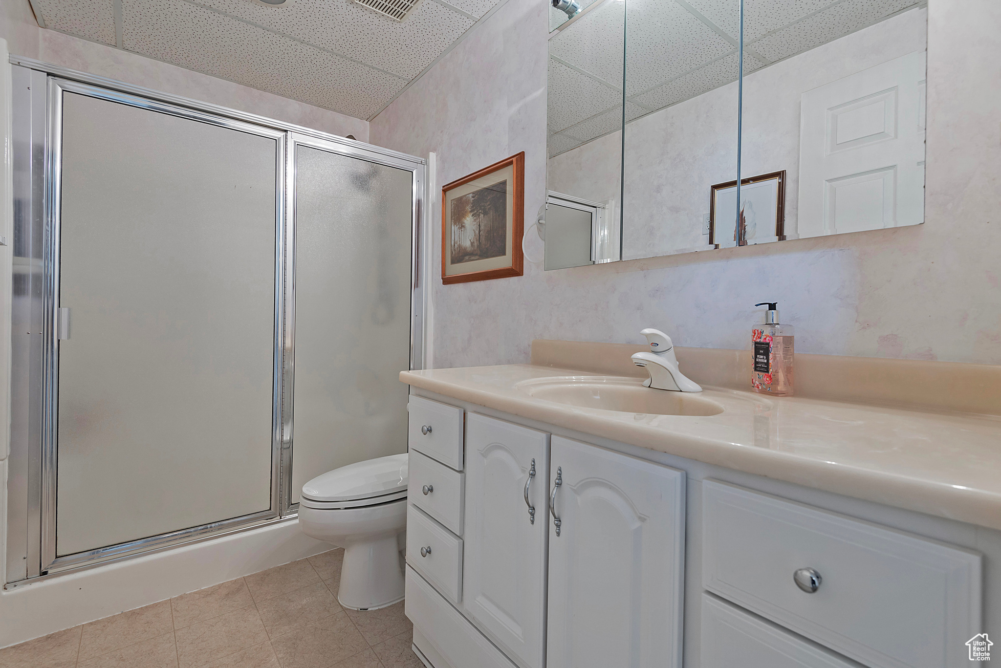 Bathroom featuring a paneled ceiling, vanity, tile patterned floors, and walk in shower