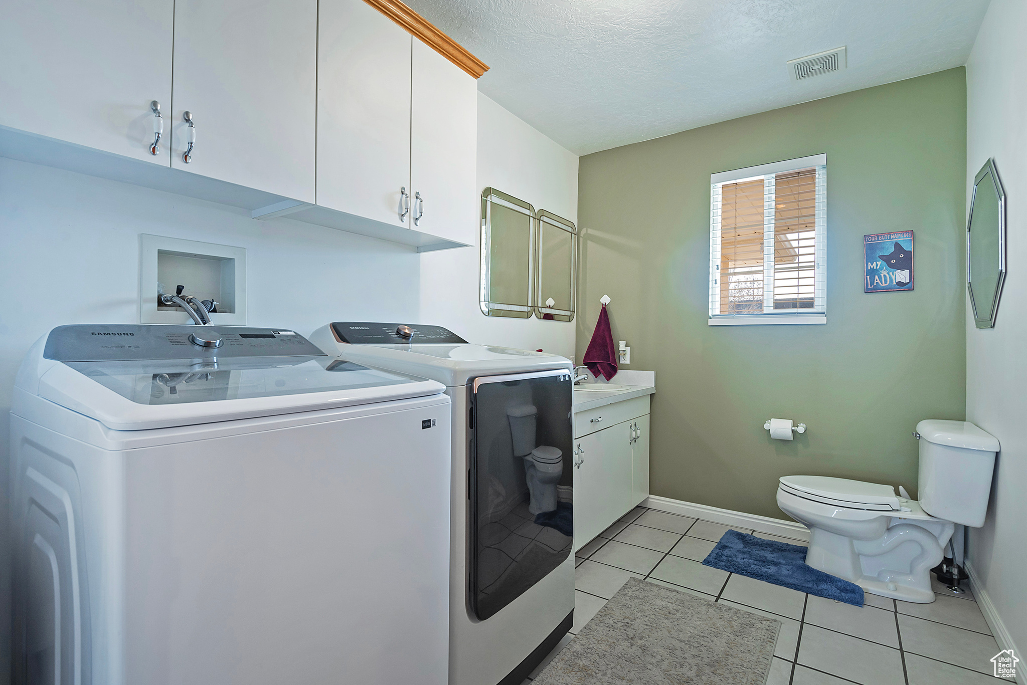 Laundry area featuring washer and clothes dryer, light tile patterned flooring, and a textured ceiling