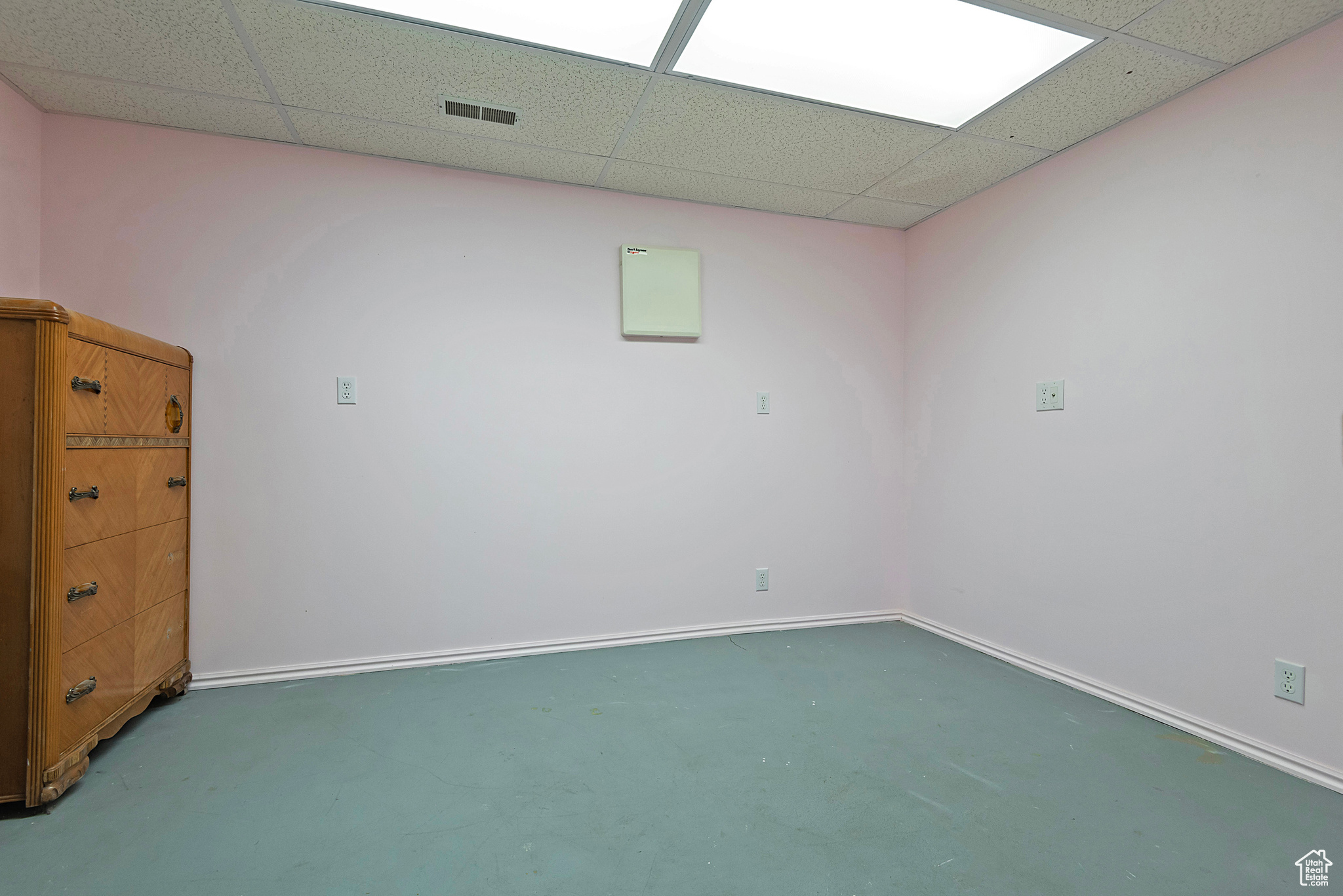 Empty room featuring a drop ceiling and concrete flooring