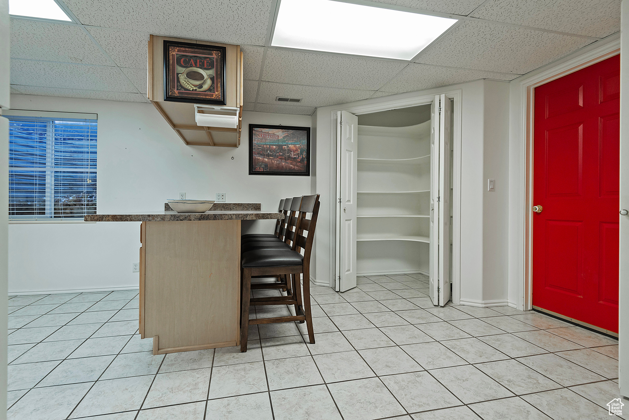 Interior space featuring a kitchen bar, a drop ceiling, and light tile patterned floors